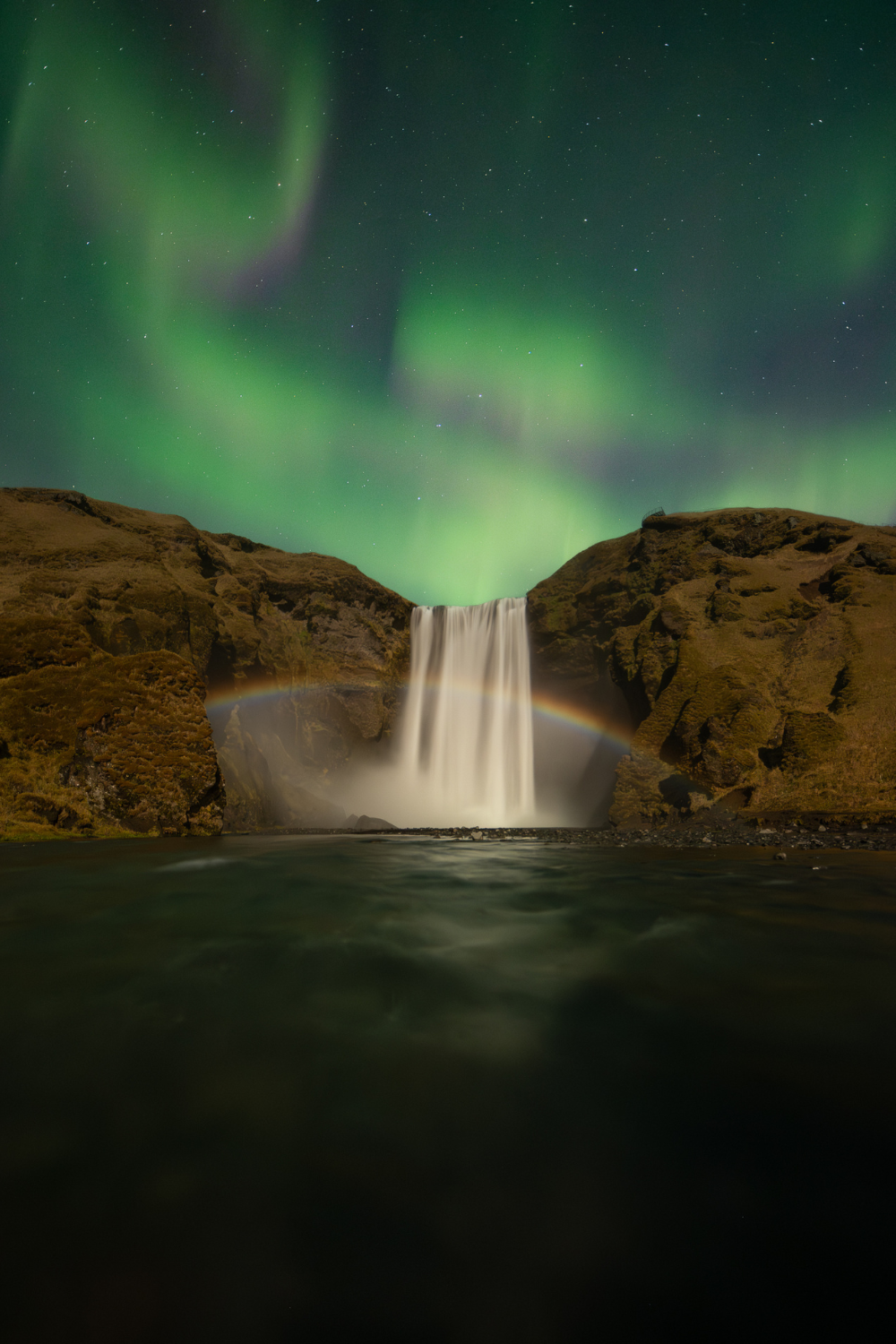 Skogafoss avec les aurores boréales et un arc-en-ciel lunaire