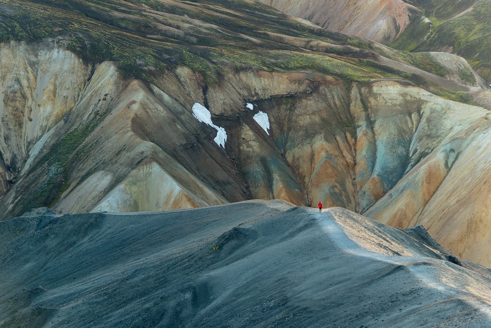 Une personne en rouge marche au coucher de soleil sur une montagne dans les Hautes-Terres d'Islande