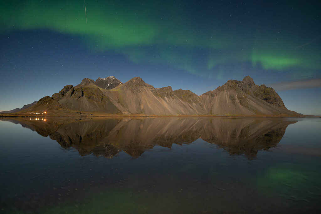 Auroras above Stokksnes mountain in Iceland in winter with a reflection