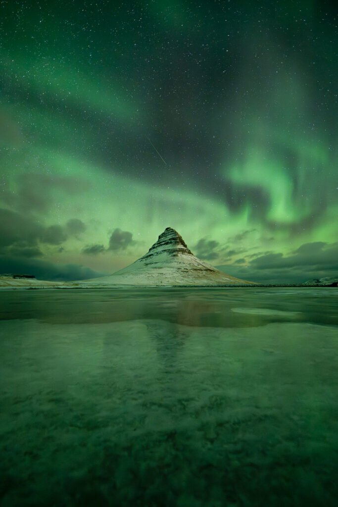 Aurores vertes et violettes avec une étoile filante au dessus du Kirkjufell en Islande