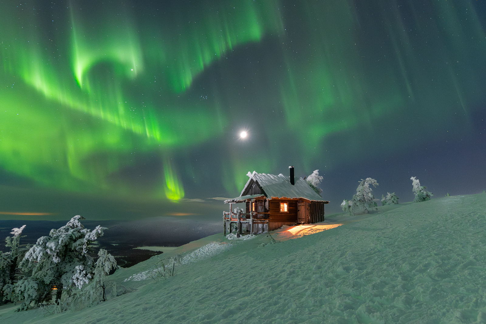 Composition photo d’aurores boréales avec une cabane éclairée au premier plan