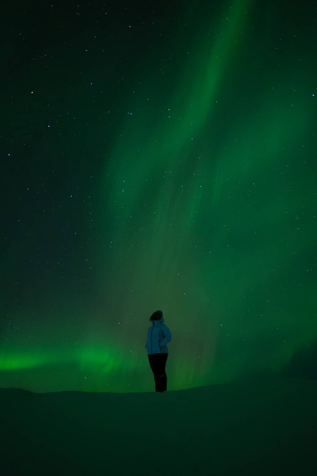 Femme sous les aurores boréales en Islande, profitant du spectacle naturel