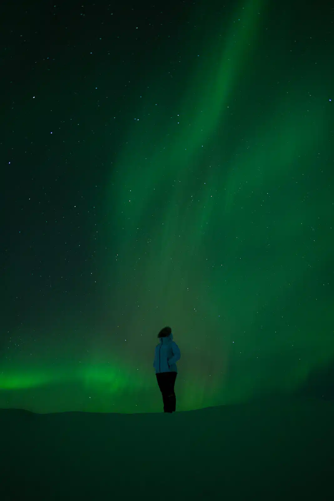 Woman under Northern Lights in Iceland, enjoying the natural spectacle