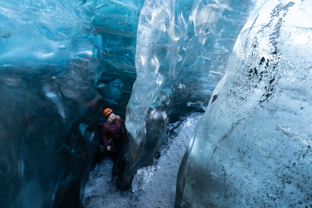 Femme qui observe les fissures et textures de la glace sur un glacier islandais