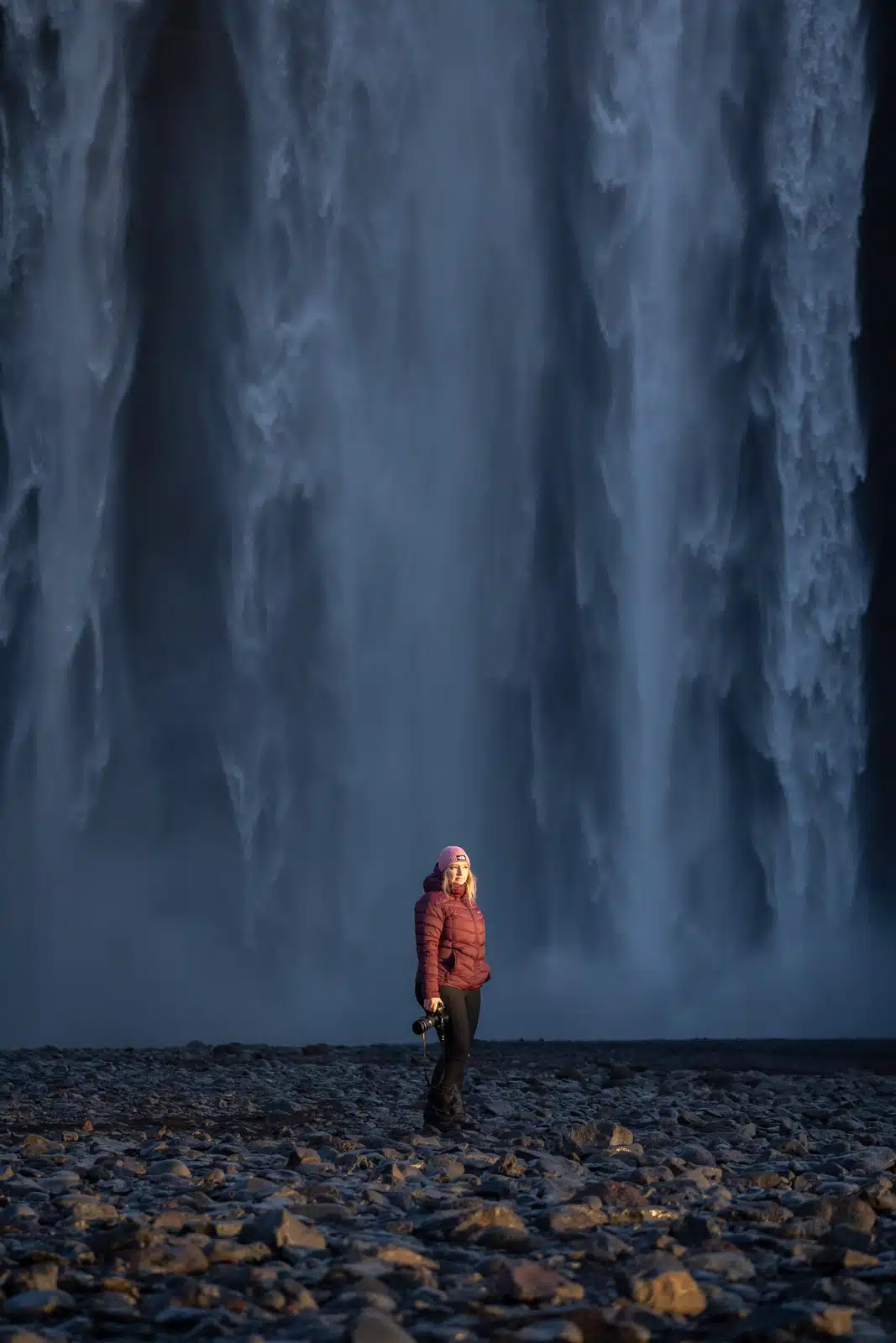Femme équipée d'une doudoune chaude devant Skogafoss, une cascade islandaise