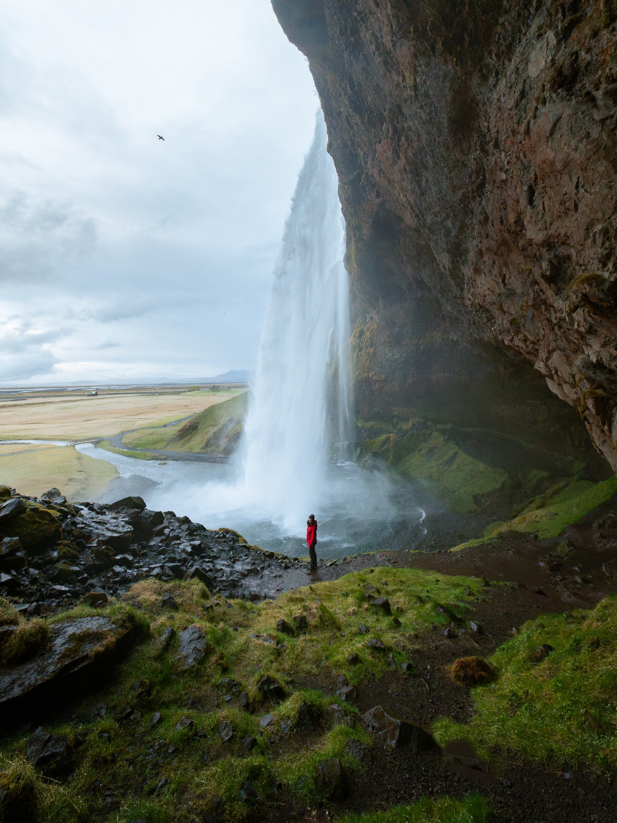 Une femme passe derrière la cascade de Seljalandsfoss en Islande