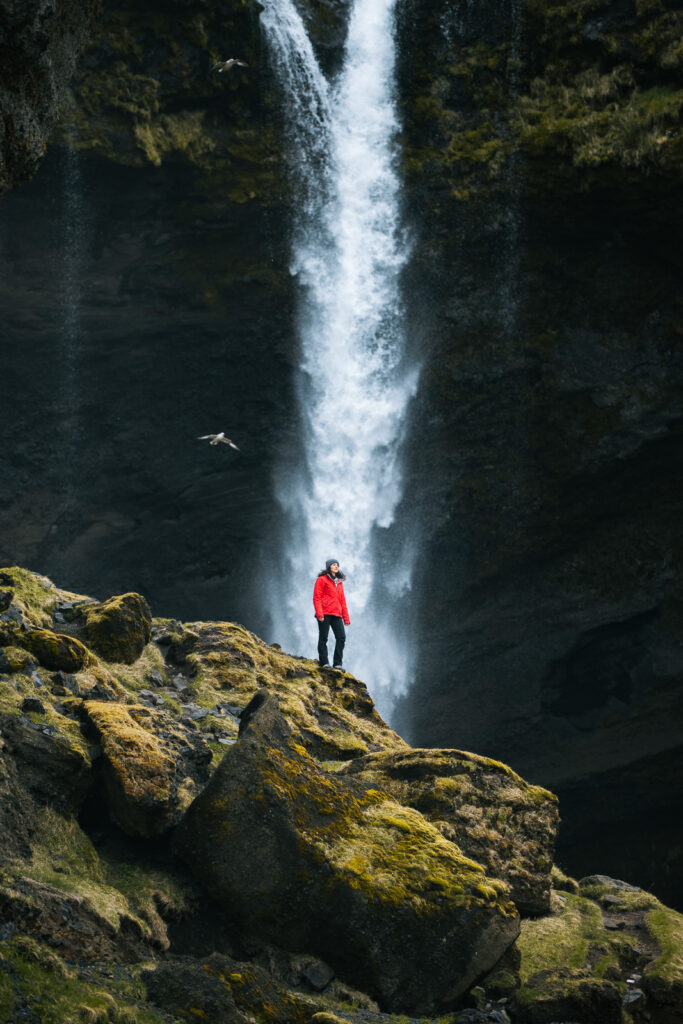 Une femme se tient devant Kvernufoss