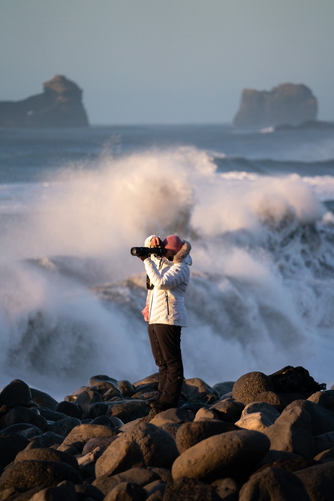 Une femme photographie une tempête sur la plage de Reynsifjara en Islande