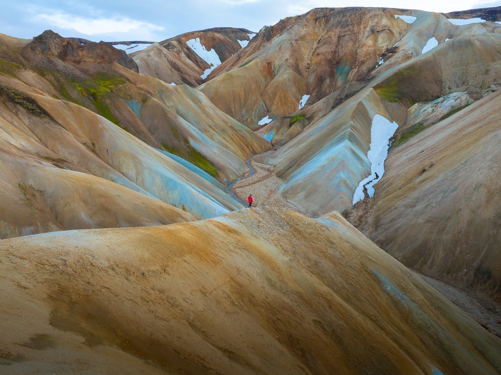 Femme marchant sur la crête au milieu des montagne colorées de Landmannalaugar