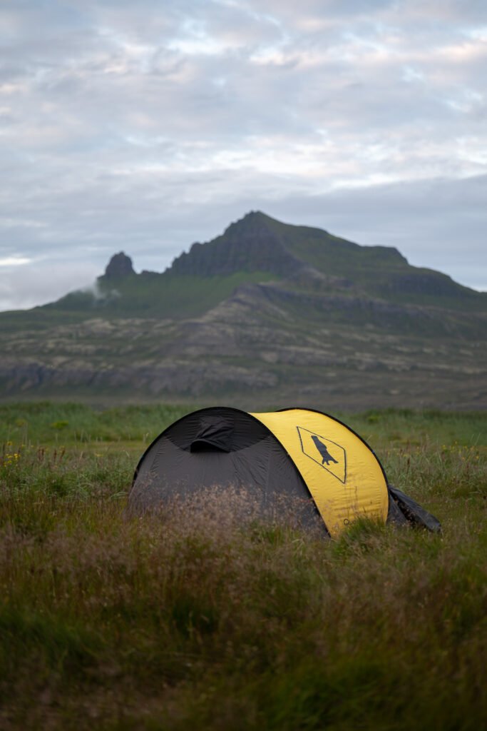 Photographie d'une tente devant la corne de Hornbjarg en Islande