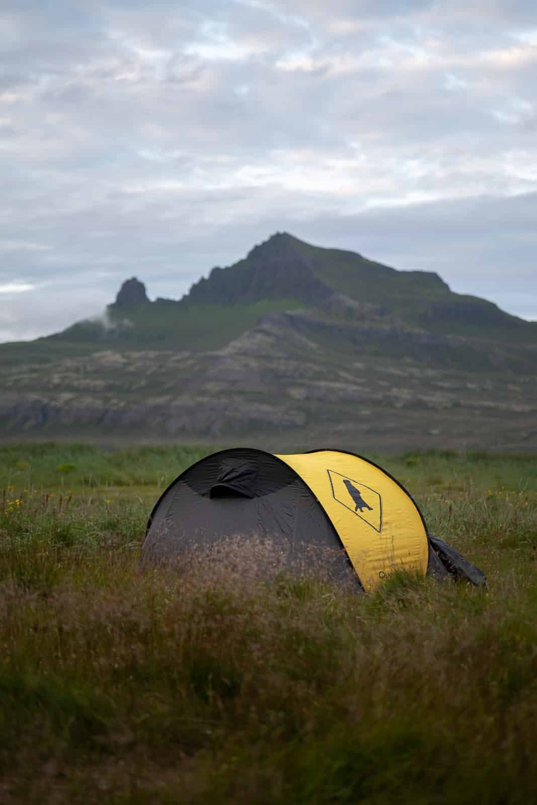 Photographie d'une tente devant la corne de Hornbjarg en Islande